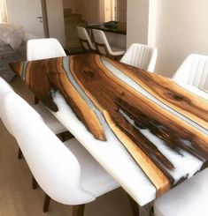 a dining room table with white chairs and a large wooden slab on it's center