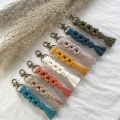 six different colors of tasselled keychains on a white sheet with feathers