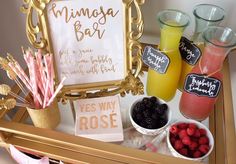 a tray filled with drinks and fruit next to a framed sign that says mimisa bar