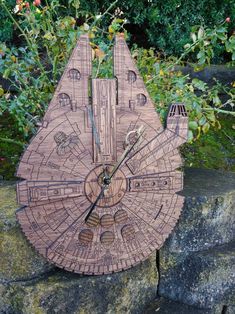 a wooden star trek ship clock sitting on top of a stone wall next to trees