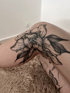 a woman laying on the floor with her legs crossed and flowers tattooed on her thigh