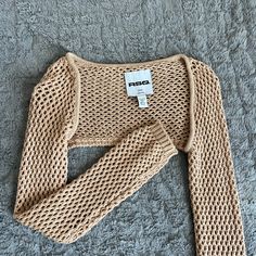 a knitted sweater with a tag on the front and neckline is laying on a gray surface