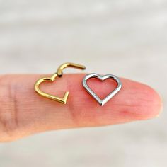 a person's finger with two heart shaped nose rings on top of each other