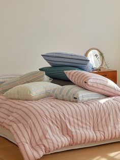 four pillows stacked on top of each other on a bed in a room with white walls