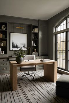 an office with gray walls and wooden floors, built in bookcases on either side of the desk