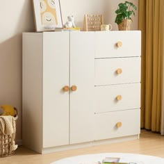 a white dresser with wooden knobs in a child's playroom or bedroom