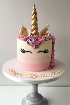 a pink and white cake with a unicorn's face on top