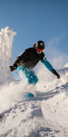 a man riding a snowboard down the side of a snow covered slope