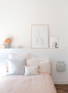 a bed with white sheets and pink pillows