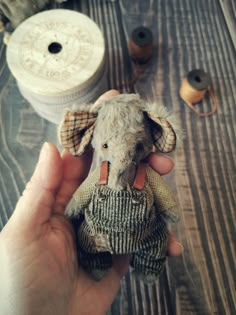 someone is holding an old stuffed elephant in their hand and sewing thread on the table