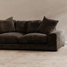 a brown couch sitting on top of a carpeted floor next to a white wall