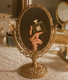 a person's hand is holding up a perfume bottle in front of a mirror