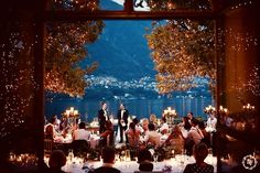 a group of people sitting at tables in front of a window with lights on it