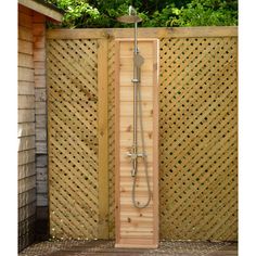 an outdoor shower in the middle of a wooden fence with trees and bushes behind it