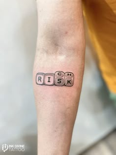 a person with a black and white tattoo on their arm that says, risk