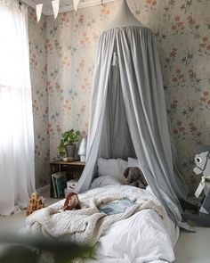 a canopy bed in the corner of a room with flowers on the walls and curtains