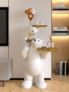 a large white polar bear holding a tray with gold balloons on it's head