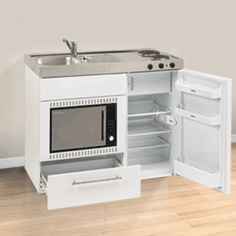 a small white kitchen with an oven and sink in the corner, next to a wall mounted refrigerator