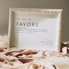 a white framed sign sitting on top of a bed next to a pile of blankets