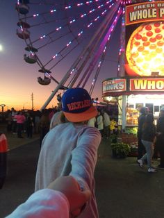 a person standing in front of a ferris wheel at night