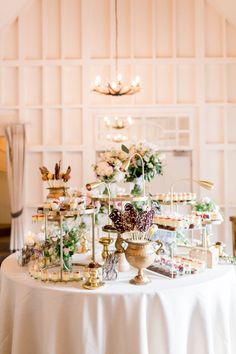 a table topped with lots of desserts on top of a white cloth covered table