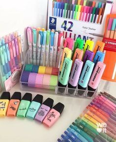 many different colored pens and markers are on display in plastic containers with dividers to keep them organized