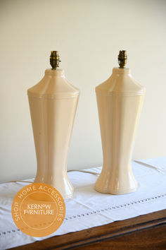 two cream colored vases sitting on top of a white tablecloth covered table cloth