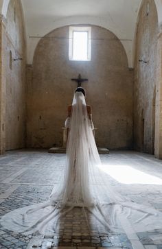 a woman in a wedding dress is standing in an old building with stone floors and arches