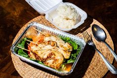 a tray with chicken, rice and lettuce on it next to a fork