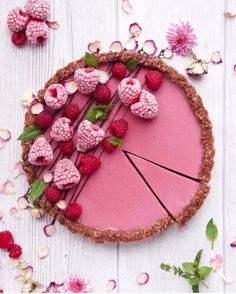 a pie with raspberries and other toppings on it sitting on a table