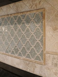 a kitchen counter with a tile design on the wall above it and a stove top