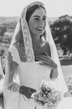 a woman in a wedding dress and veil smiles as she walks down the aisle with her bouquet