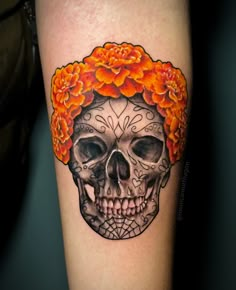 a woman's arm with a skull and flower crown on top of her head