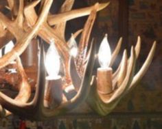 a chandelier made out of antlers with candles in the middle of it