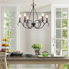 a chandelier hanging over a dining room table with plates and bowls on it