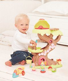 a toddler playing with a toy tree house on the floor in a living room