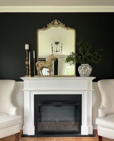 a living room with two chairs and a fire place in front of a mirror on the wall