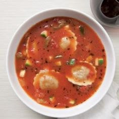 a bowl of soup with dumplings in it on a table next to a spoon