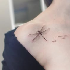 a woman's shoulder with a small dragonfly tattoo on the left side of her upper arm