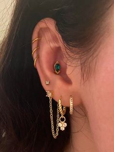 a close up of a person's ear with gold chains and earrings on it