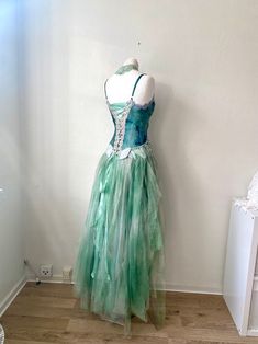 a dress is displayed on a mannequin in front of a white wall and wooden floor