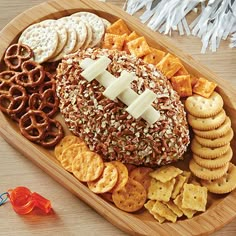 a wooden platter filled with cheese, crackers and pretzels