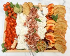 an assortment of appetizers on a platter with cheese, crackers and tomatoes