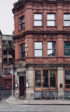 an old brick building with two bicycles parked in front of it on the street corner