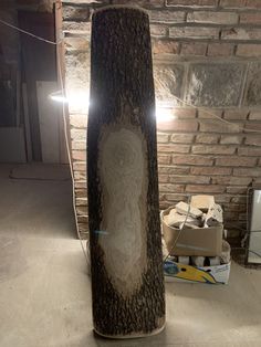 a tree trunk with a carved face on it in a room next to a brick wall