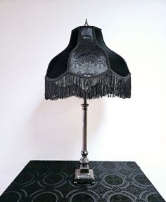 a lamp that is sitting on top of a table with a black shade over it