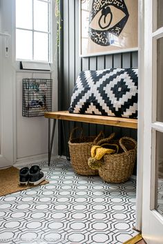 the entryway is decorated with black and white tiles, baskets, and pictures on the wall