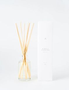 reeds in a clear glass vase next to a white box