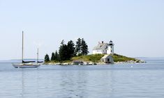 an island with a sailboat in the water and a lighthouse on it's side