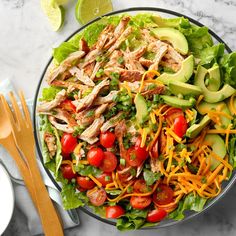 a salad with chicken, lettuce, tomatoes, cheese and avocado